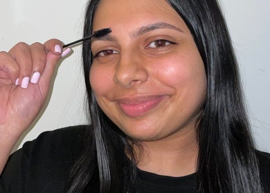 Smiling woman using mascara wand on eyebrows at SKULPTED, Fairfield, New South Wales, AU.