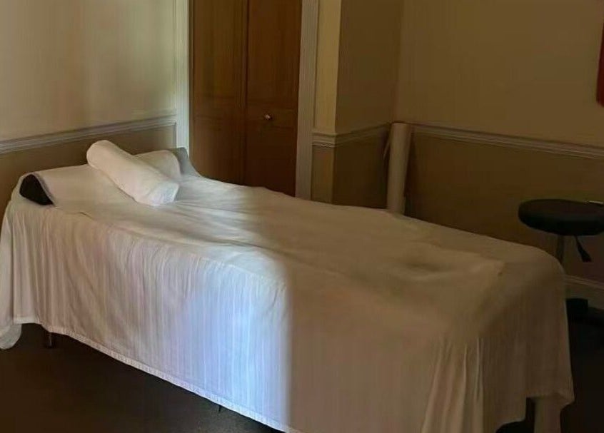 Massage therapy room at Acupressure Spa, Burke, Virginia, US with a neatly arranged bed and stool.