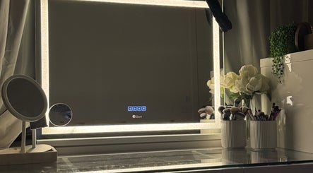 Elegant vanity mirror at Artistry By Nur, Melbourne, Victoria, AU, with lights, makeup brushes, and flowers.