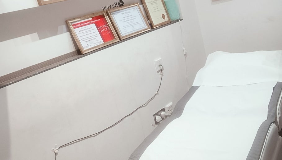 Certificate-decorated room at Physical Therapy in Greenford, England, GB featuring a prepared treatment bed.