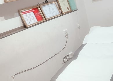 Certificate-decorated room at Physical Therapy in Greenford, England, GB featuring a prepared treatment bed.