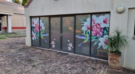 Colorful window art at The Look Hair Gallery, Potchefstroom, North West, ZA, showcasing hummingbird and flowers.