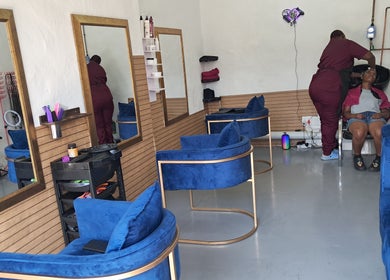 A stylist works with a client in a cozy salon at Rooted Hair Co, Pretoria, Gauteng, ZA.