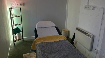 Cozy therapy room at The_thera_pt, Blackburn, Scotland, GB, featuring comfortable massage table and softly lit shelves.
