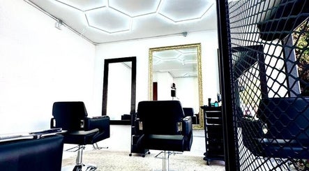 Interior moderno de O Cabelo, peluquería en Ciudad De México, MX, con sillas negras y espejos grandes.