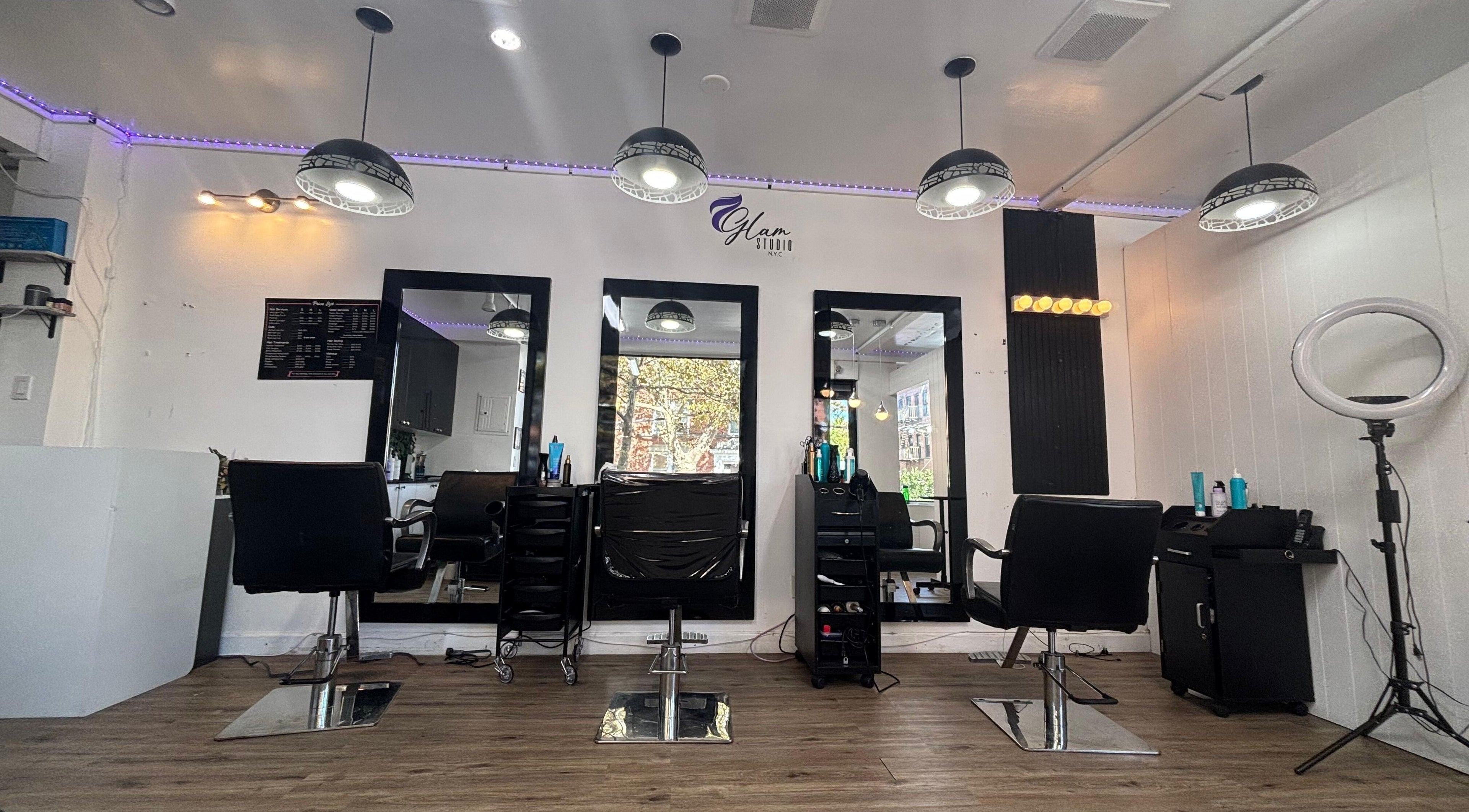 Modern salon interior at Glam Studio NYC, New York, New York, US with stylish black chairs and mirrors.