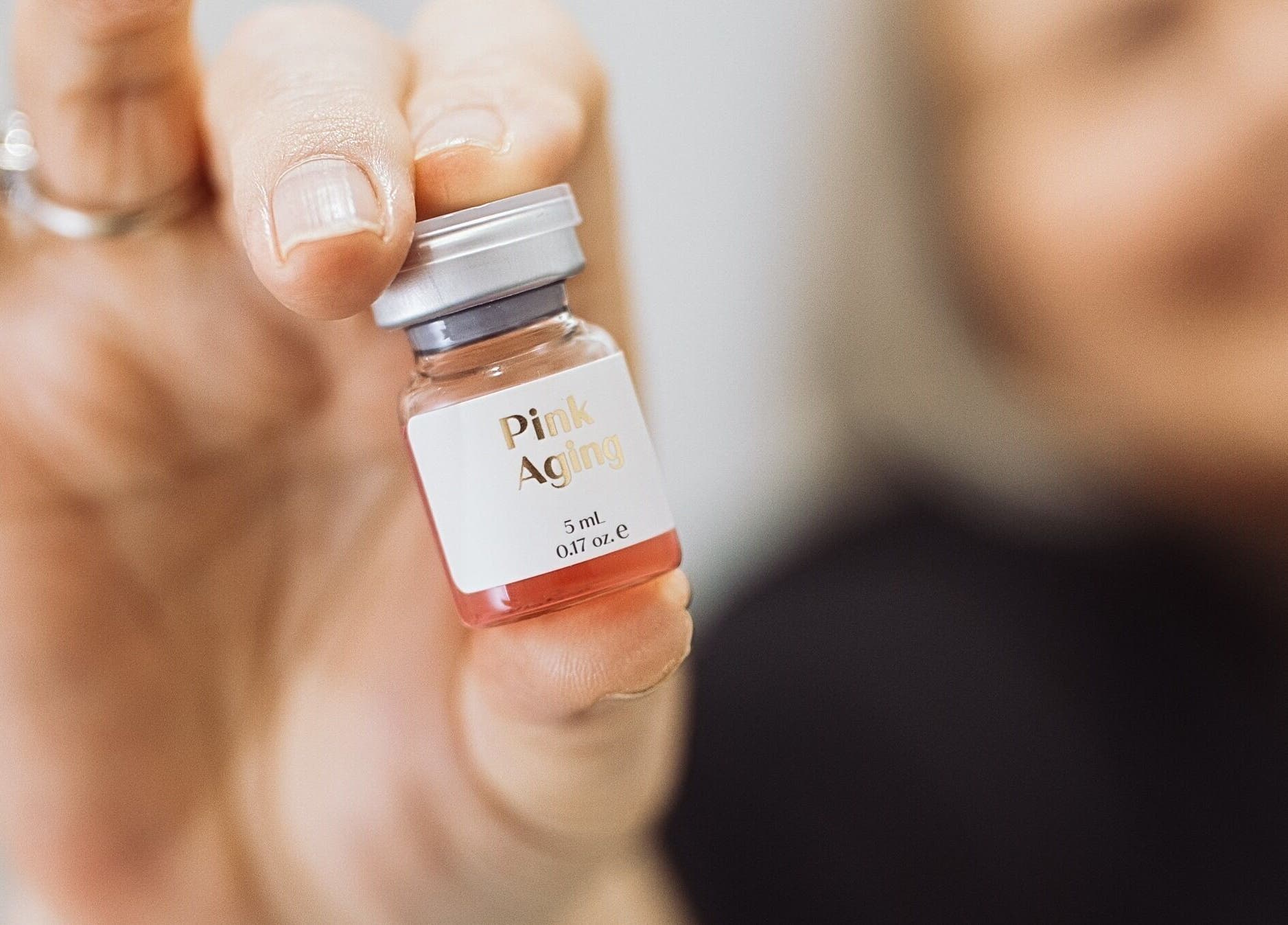Hand holding pink aging serum vial at Hands-On Laser Cosmetic Clinic, Melbourne, Victoria, AU.