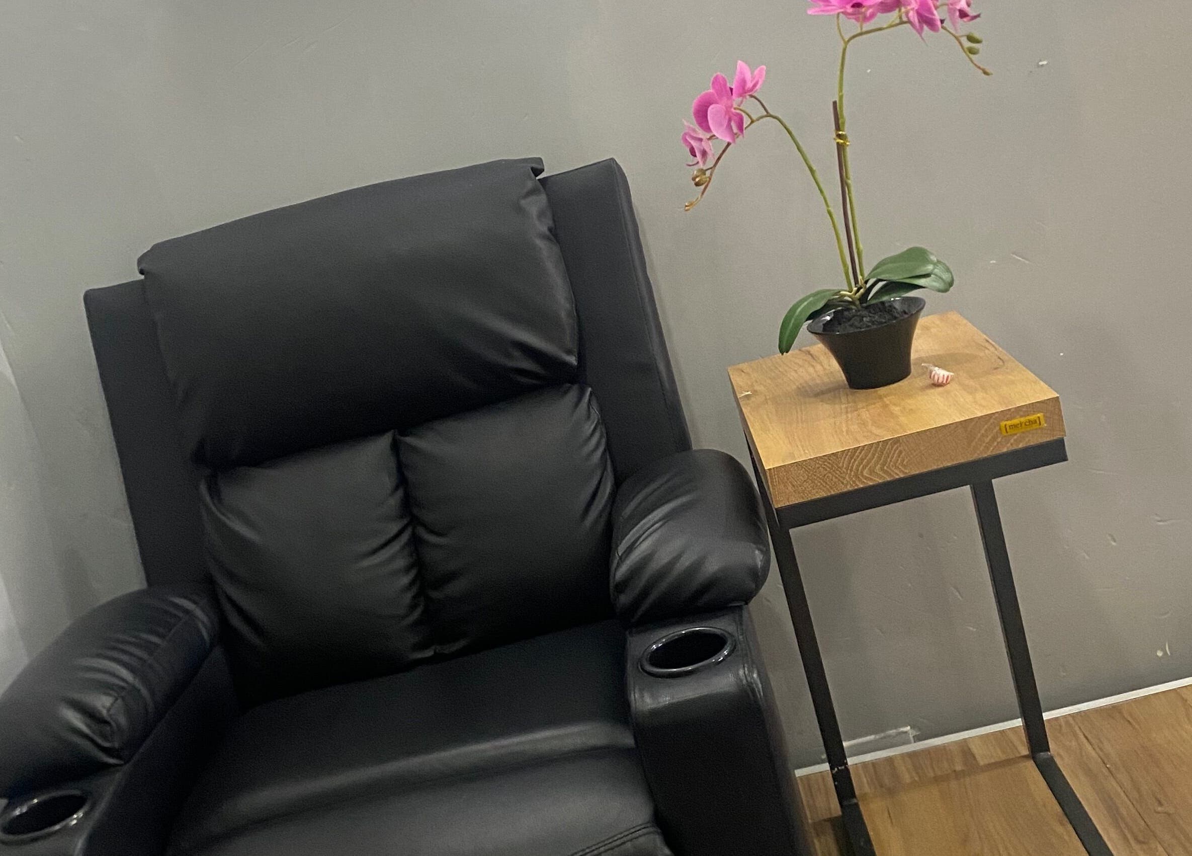 Luxurious black recliner at Snique Allure, Montego Bay, St. James Parish, JM beside an elegant orchid.