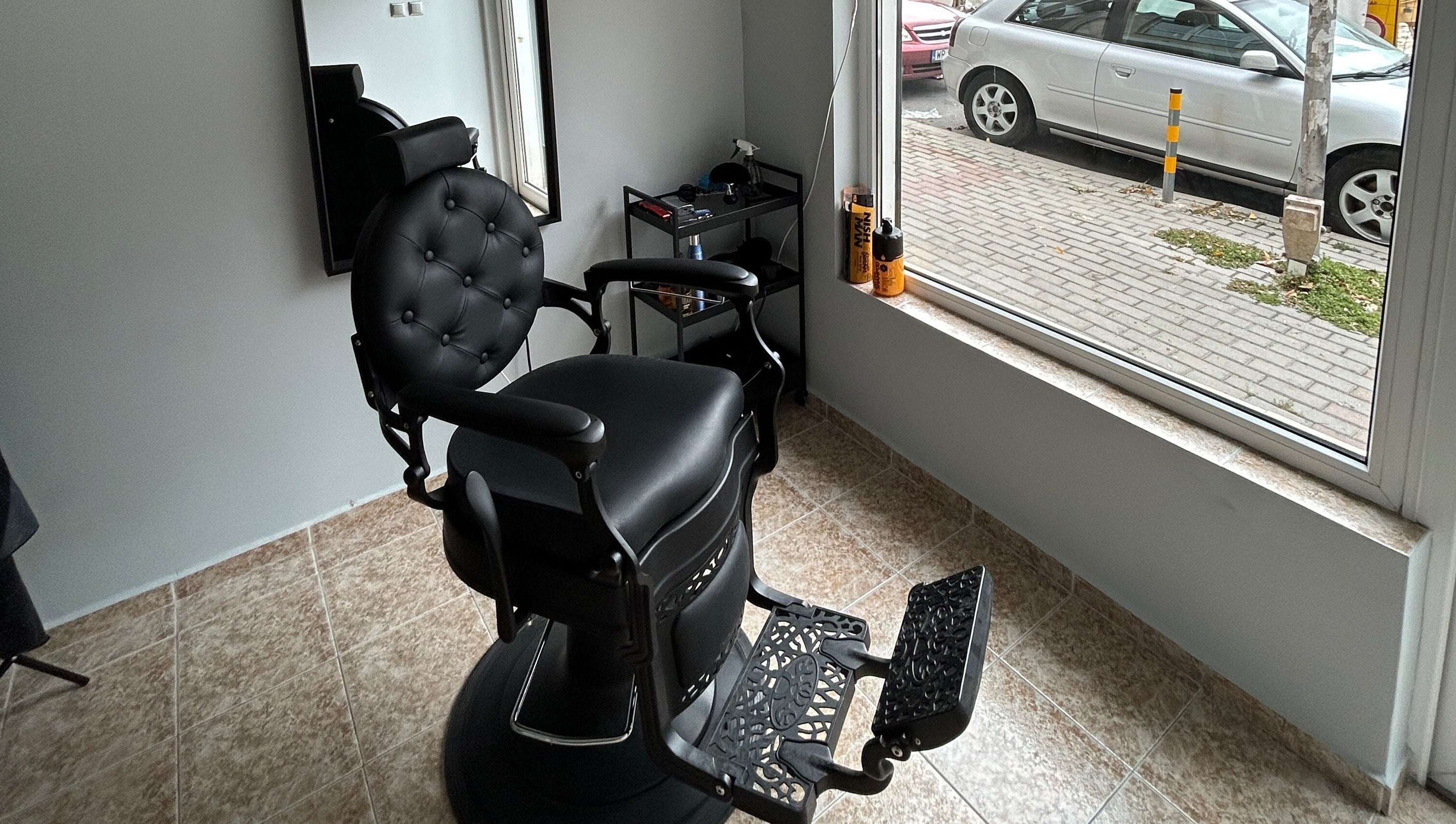 Modern black barber chair at MiriCutz in Varna, Varna, BG, near a bright window with street view.