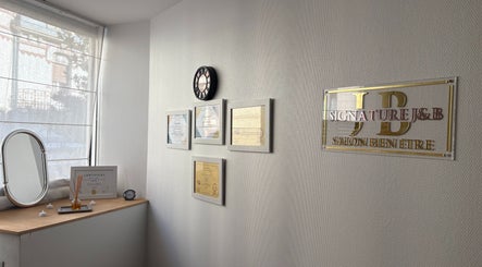 Mur de distinctions au salon Signature J&B à Tarbes, Occitanie, FR, avec certificats et miroir.