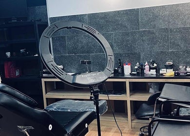 Εσωτερικό του INK FAME TATTOO SHOP στο Ίλιον, GR, με εξοπλισμό φωτισμού και καρέκλα τατουάζ.