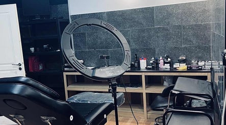 Εσωτερικό του INK FAME TATTOO SHOP στο Ίλιον, GR, με εξοπλισμό φωτισμού και καρέκλα τατουάζ.