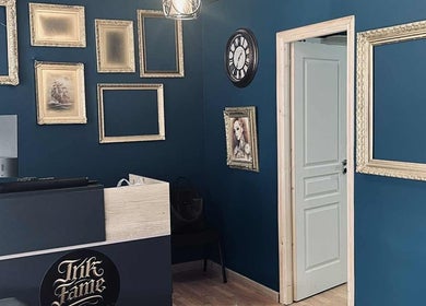Εσωτερικό του INK FAME TATTOO SHOP, Ίλιον, GR, με διακοσμητικά κάδρα και μοντέρνα διακόσμηση.