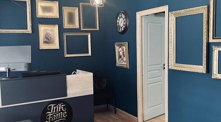 Εσωτερικό του INK FAME TATTOO SHOP, Ίλιον, GR, με διακοσμητικά κάδρα και μοντέρνα διακόσμηση.