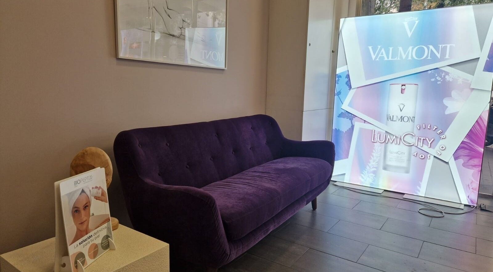 Elegante sofá violeta en Cinc Estètica, Barcelona, Catalunya, ES, con cartel publicitario de Valmont.