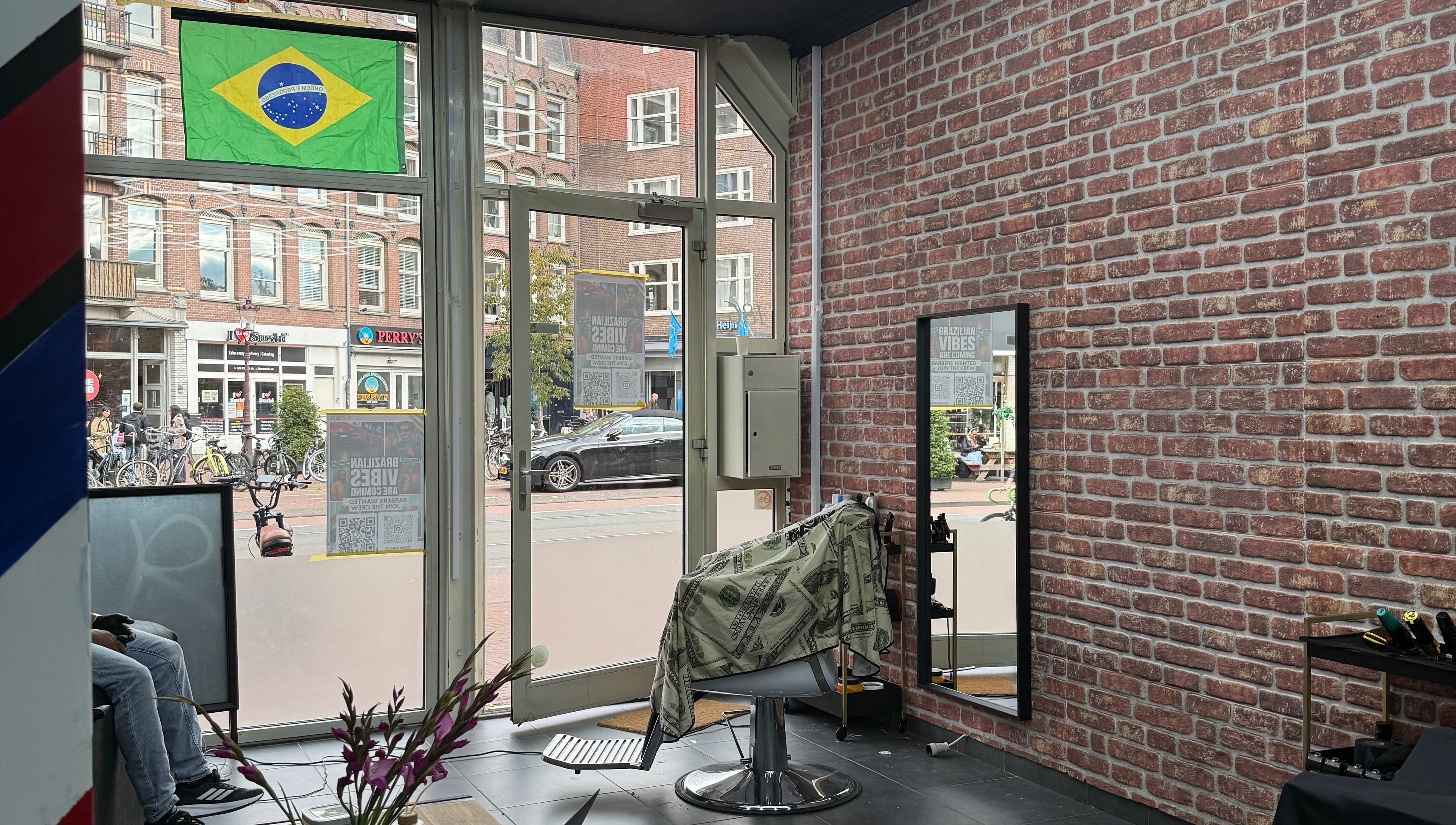 Interior da Navalhagold em Amsterdam, NL, destacando cadeira de barbeiro com bandeira do Brasil.