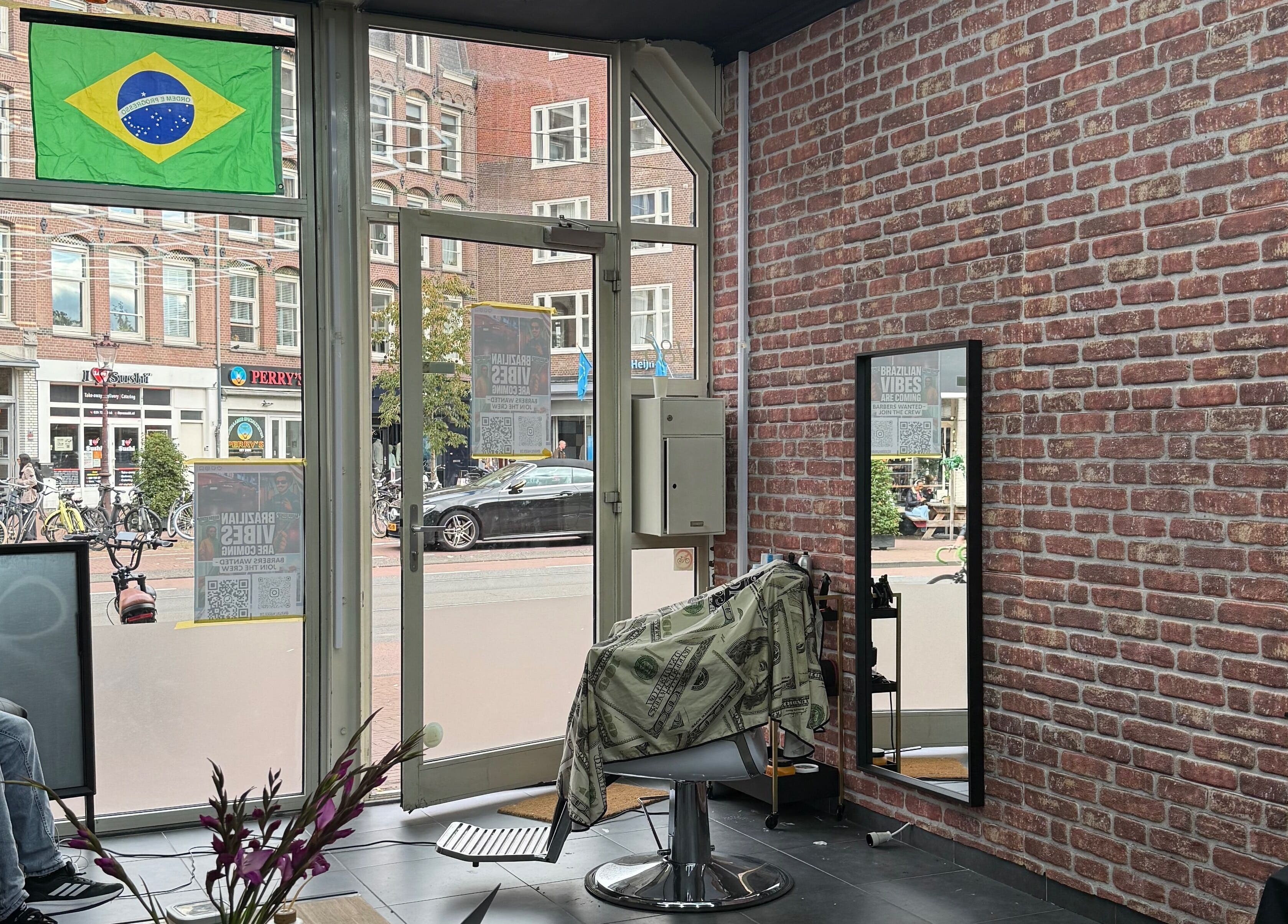 Interior da Navalhagold em Amsterdam, NL, destacando cadeira de barbeiro com bandeira do Brasil.