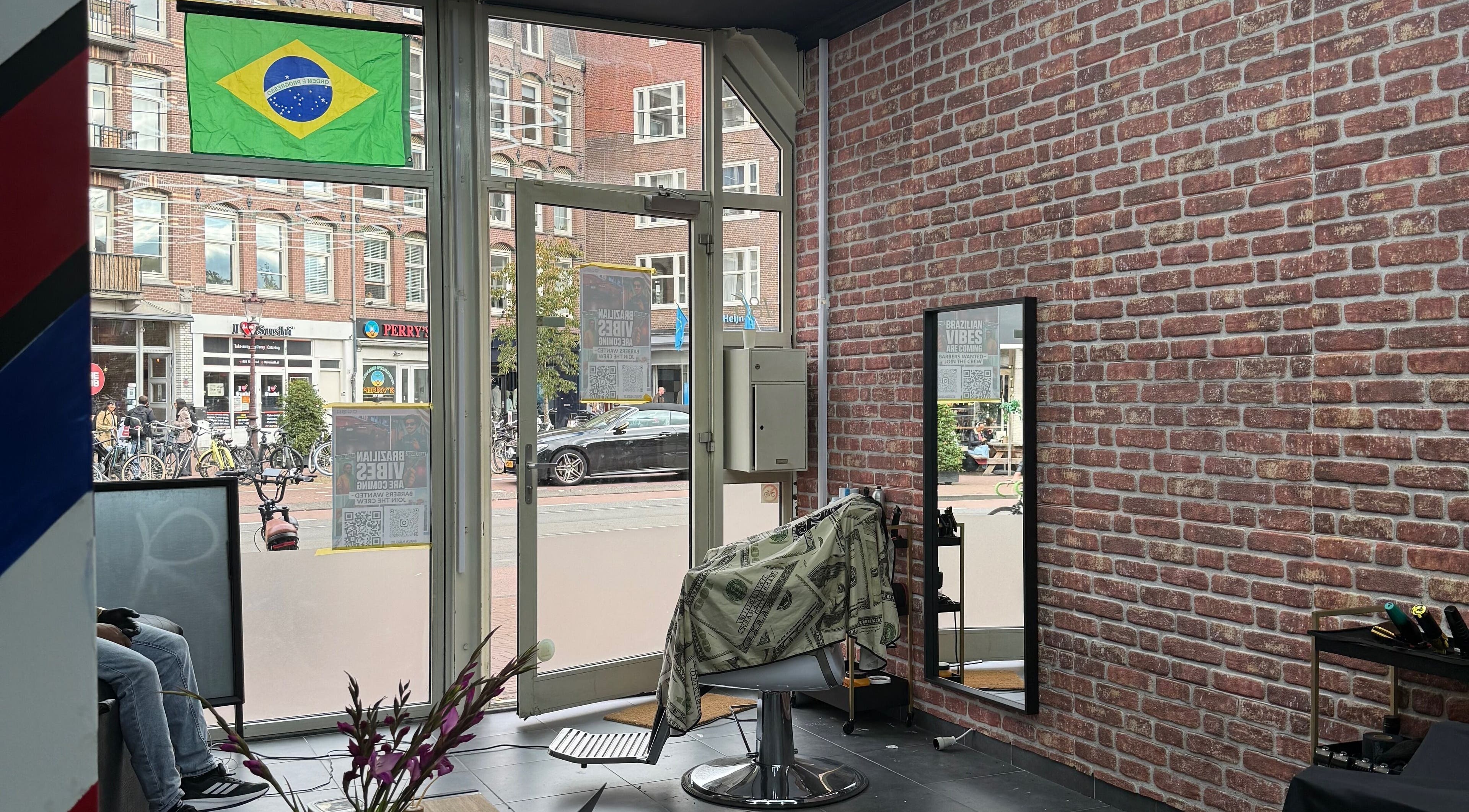 Interior da Navalhagold em Amsterdam, NL, destacando cadeira de barbeiro com bandeira do Brasil.