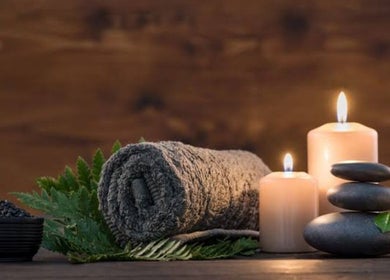 Relaxing spa scene at Cruz S&C, Yangebup, Western Australia, AU with candles, stones, and a rolled towel.