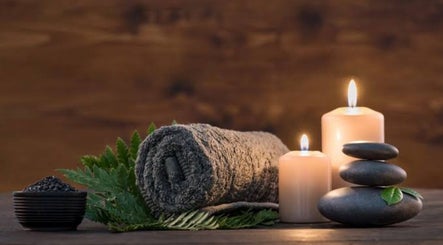 Relaxing spa scene at Cruz S&C, Yangebup, Western Australia, AU with candles, stones, and a rolled towel.