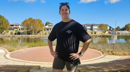 Smiling person in Cruz S&C shirt, Yangebup, Western Australia, AU, with serene lake backdrop.