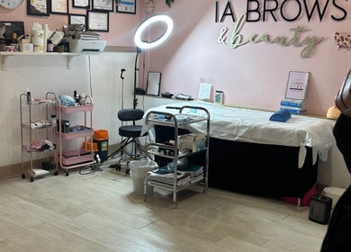 IA Brows and Beauty, London, England, GB. Cozy treatment room with bed, shelves, and lighting.