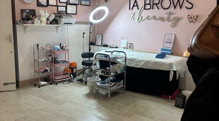 IA Brows and Beauty, London, England, GB. Cozy treatment room with bed, shelves, and lighting.