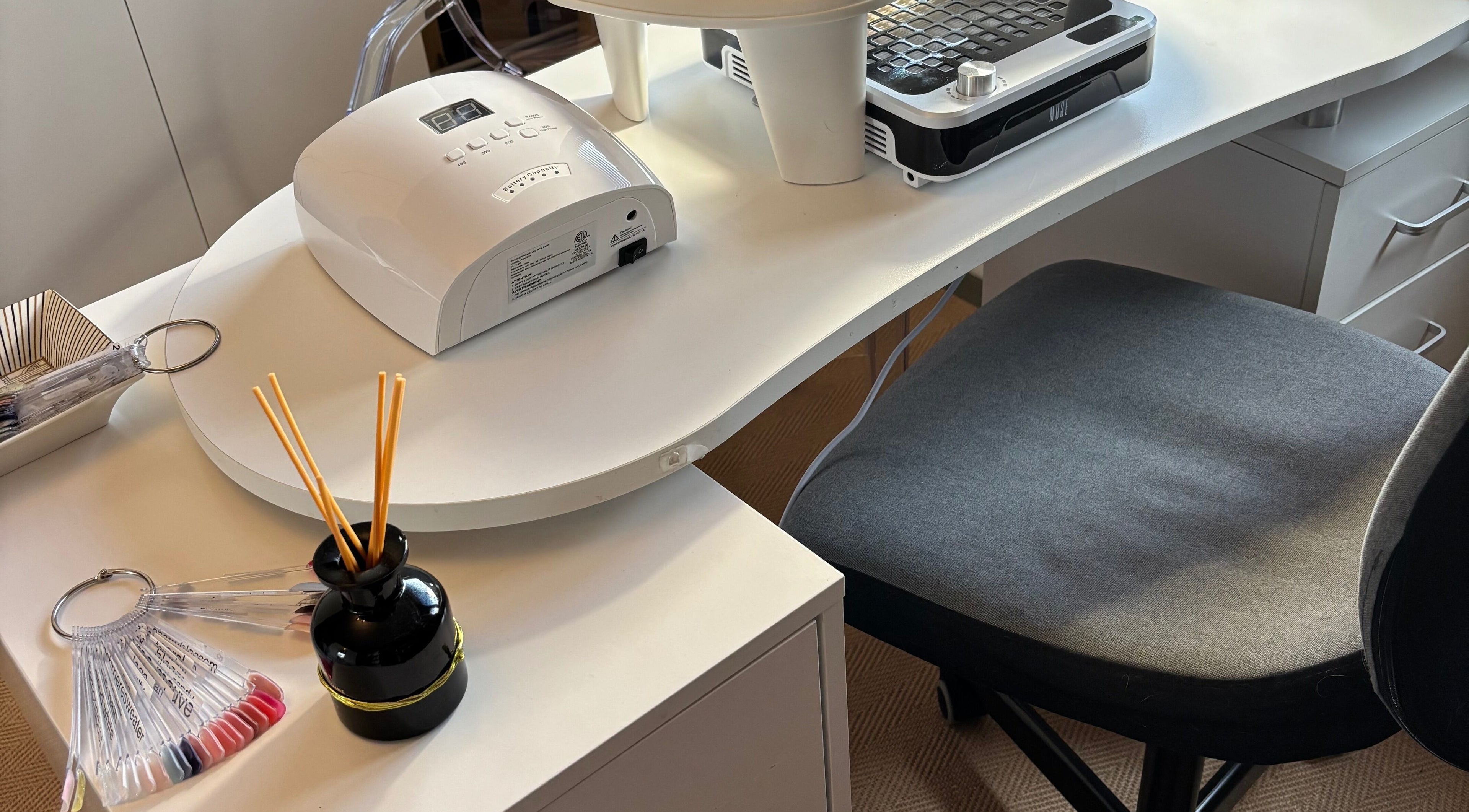 Chic manicure station at Nails@32, Laleston, Wales, GB, featuring a modern nail dryer and polish samples.