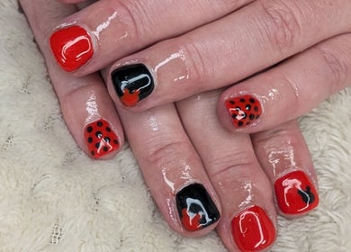 Stylish red and black nail art at Shbeautyfife, Cowdenbeath, Scotland, GB showcasing expert design.