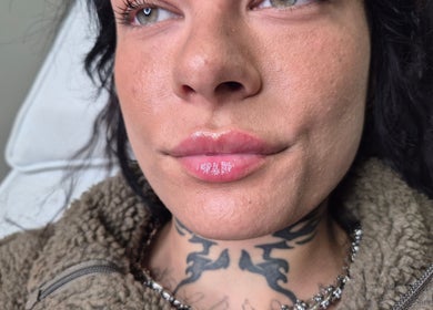 Close-up of glossy lips and tattoo detail at beauty venue in Ipswich, England, GB.