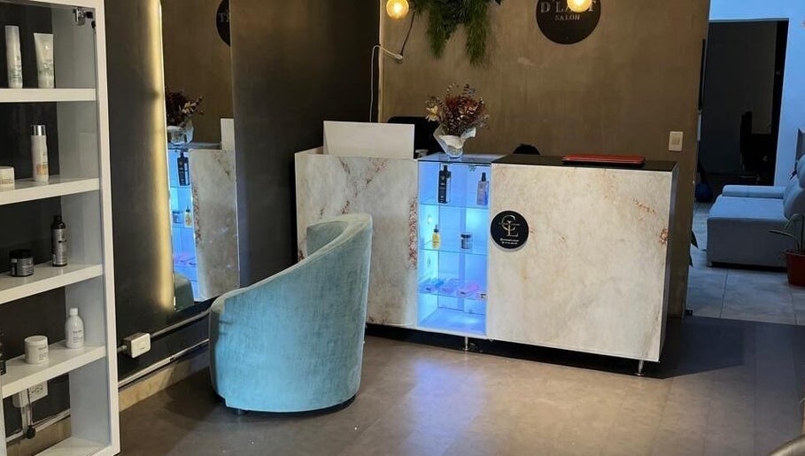 Recepción moderna en D'LART SALON, Medellín, Antioquia, CO con estantería de productos y silla azul.