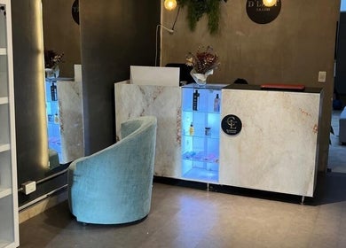 Recepción moderna en D'LART SALON, Medellín, Antioquia, CO con estantería de productos y silla azul.