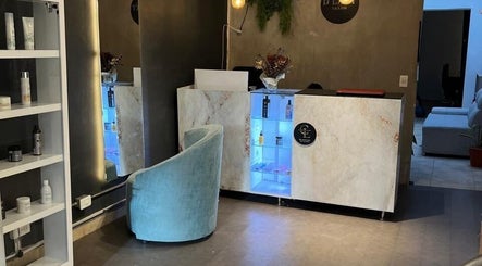 Recepción moderna en D'LART SALON, Medellín, Antioquia, CO con estantería de productos y silla azul.