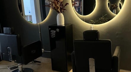 Interior de D`LART SALON en Medellín, Antioquia, CO con espejos circulares iluminados y sillas estilizadas.