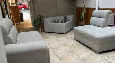 Elegante sala de espera en D'LART SALON, Medellín, Antioquia, CO, con sofás grises modernos.