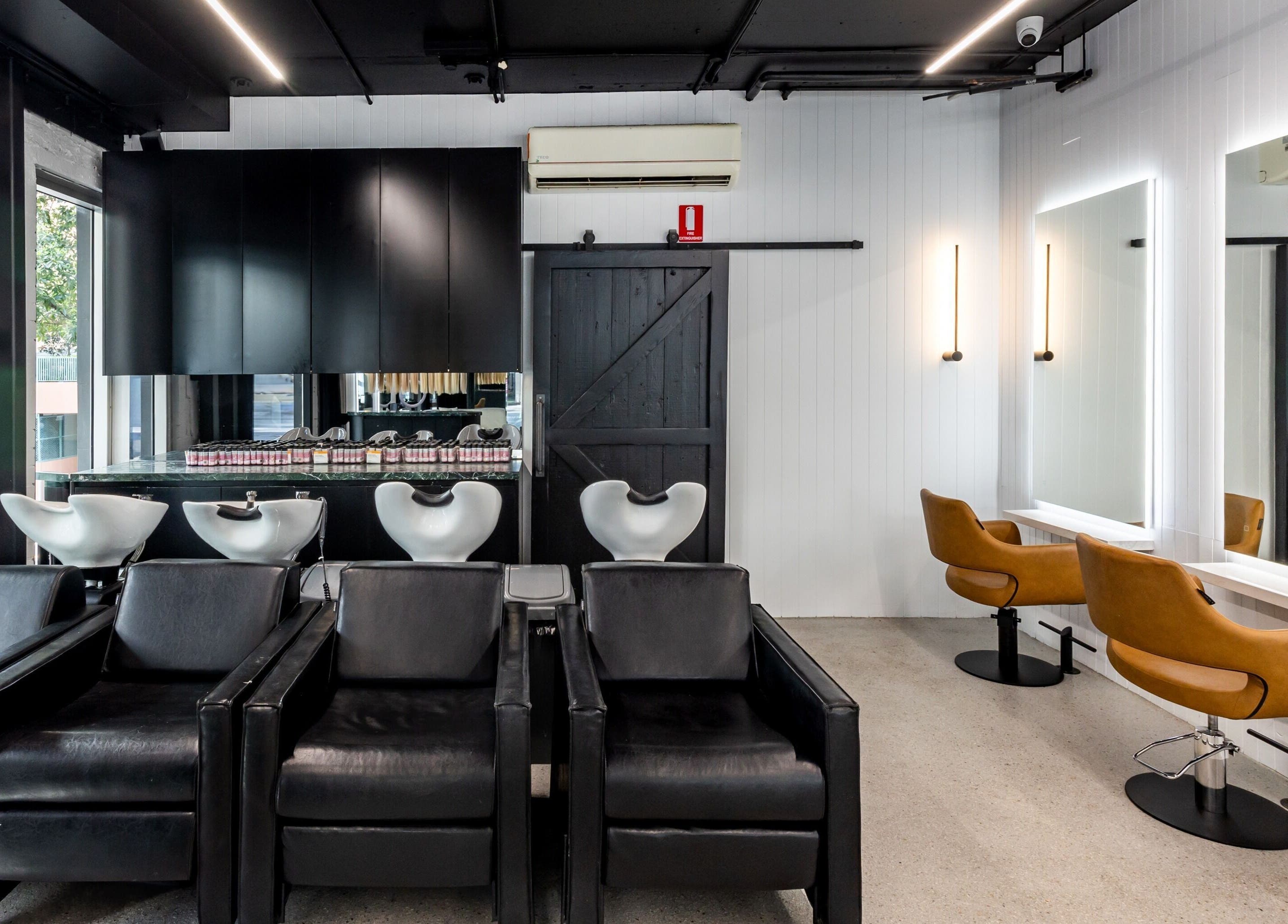 Chic interior of MAISON MANE HAIR in Bondi Junction, New South Wales, AU with sleek black and brown styling chairs.