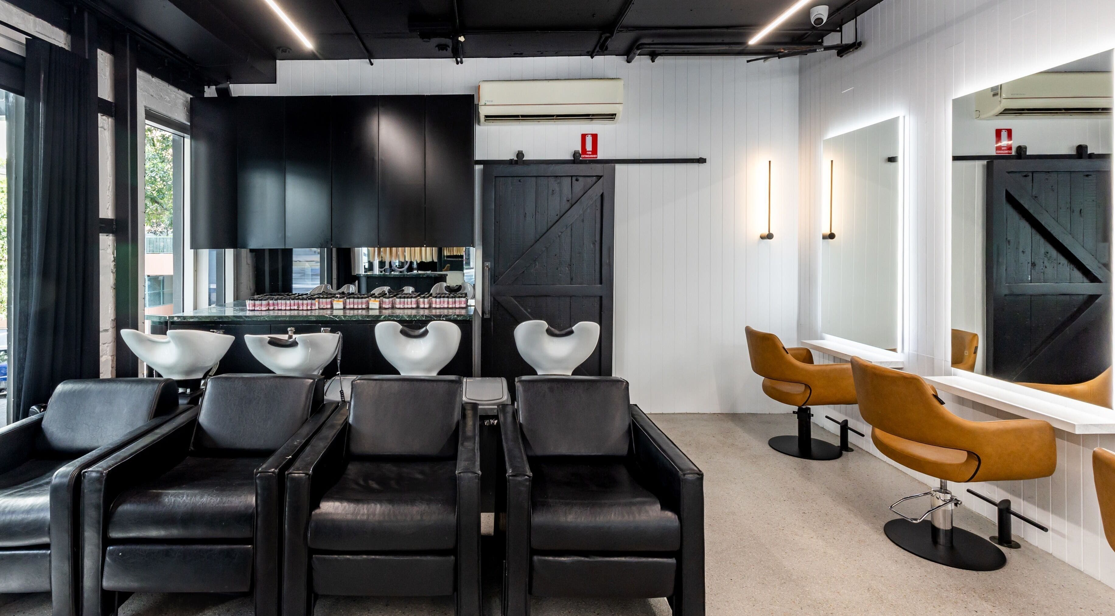 Chic interior of MAISON MANE HAIR in Bondi Junction, New South Wales, AU with sleek black and brown styling chairs.