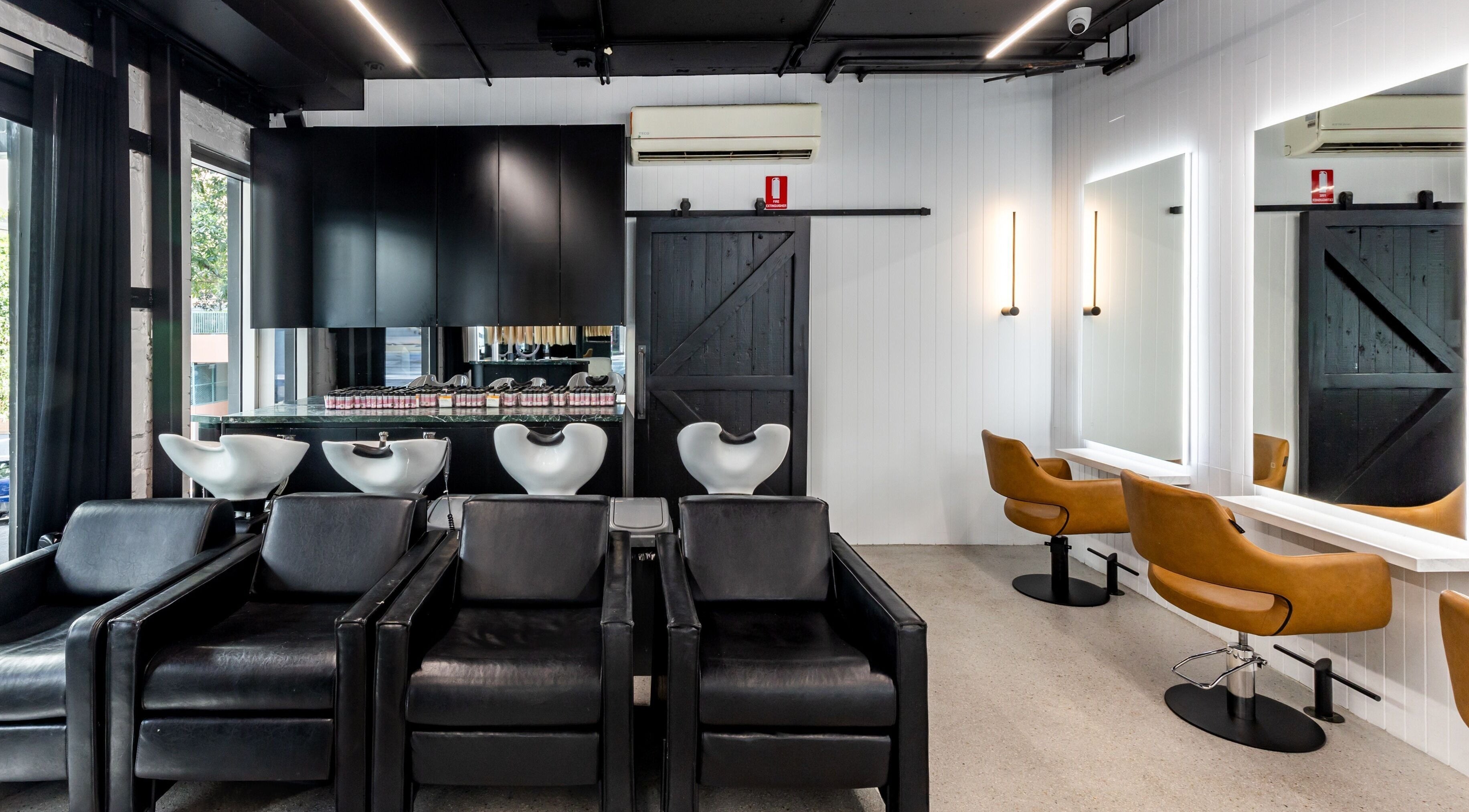 Chic interior of MAISON MANE HAIR in Bondi Junction, New South Wales, AU with sleek black and brown styling chairs.