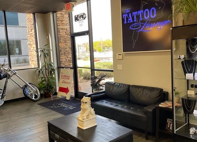Interior of The Tattoo Lounge in Mesa, Arizona, US, featuring a sleek black couch and a display case with jewelry.