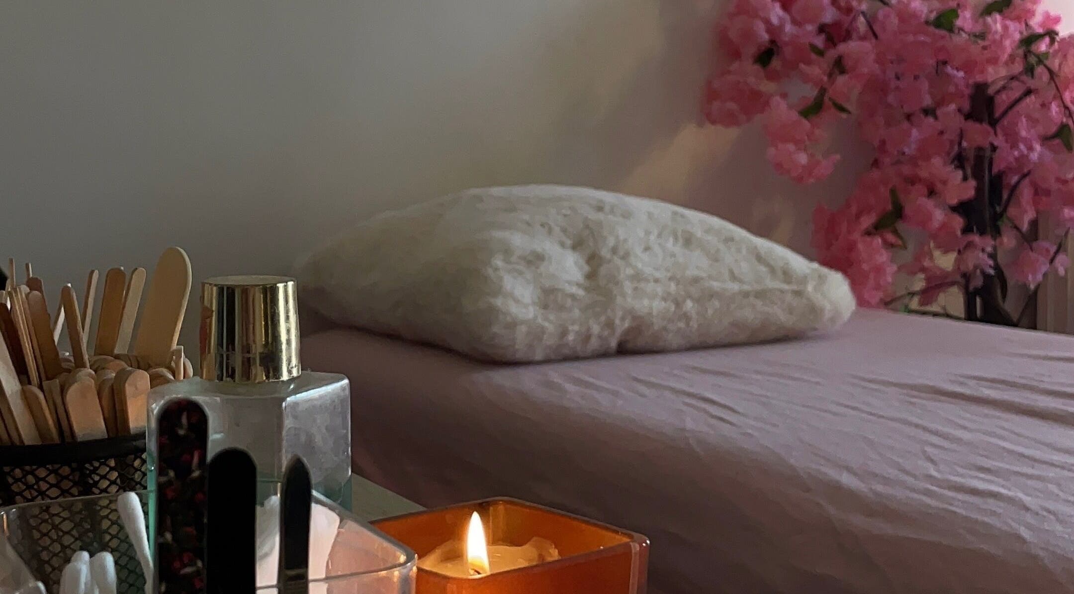 Espace de détente chez MK BEAUTY à Rivesaltes, Occitanie, FR avec lit, bougie et décor floral.