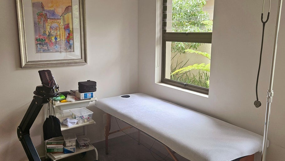 Relaxing treatment room at Island Aesthetics, Cape Town, Western Cape, ZA. Features a massage bed by a window.