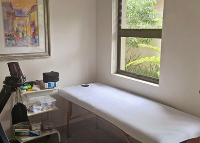 Relaxing treatment room at Island Aesthetics, Cape Town, Western Cape, ZA. Features a massage bed by a window.