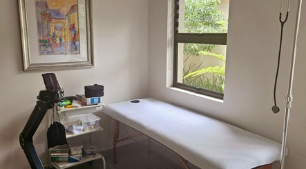 Relaxing treatment room at Island Aesthetics, Cape Town, Western Cape, ZA. Features a massage bed by a window.