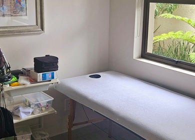 Calm treatment room at Island Aesthetics in Cape Town, Western Cape, ZA, featuring a massage table by a window.