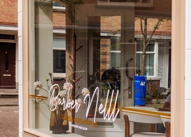 Etalage van Barber Bor in Rotterdam, Zuid-Holland, NL, met stijlvolle bloemen en interieurdetails.