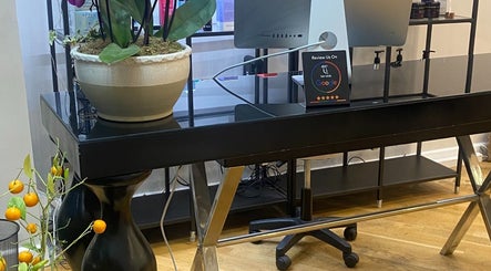 Reception desk at Chelsea Beauty, London, England, GB featuring a sleek design and a vibrant plant display.