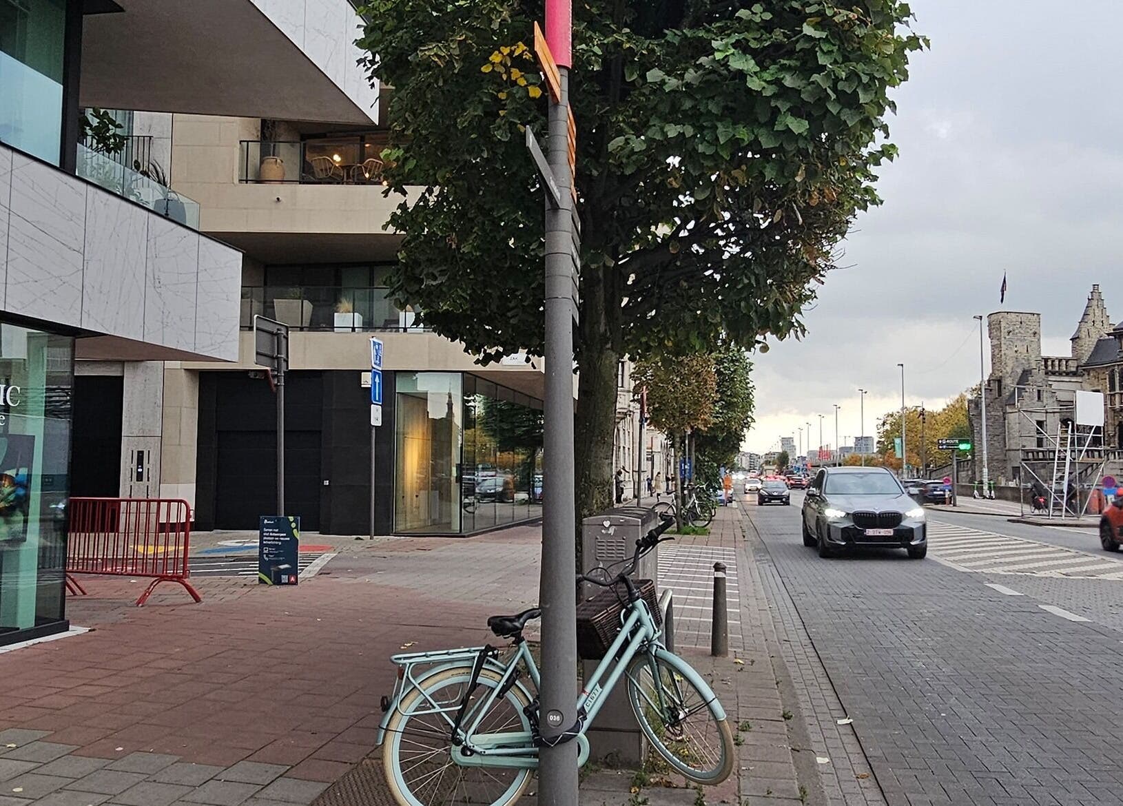 Straatbeeld van Luxim Clinic in Antwerpen, Vlaanderen, BE met fietsen en voorbijgaande auto's.