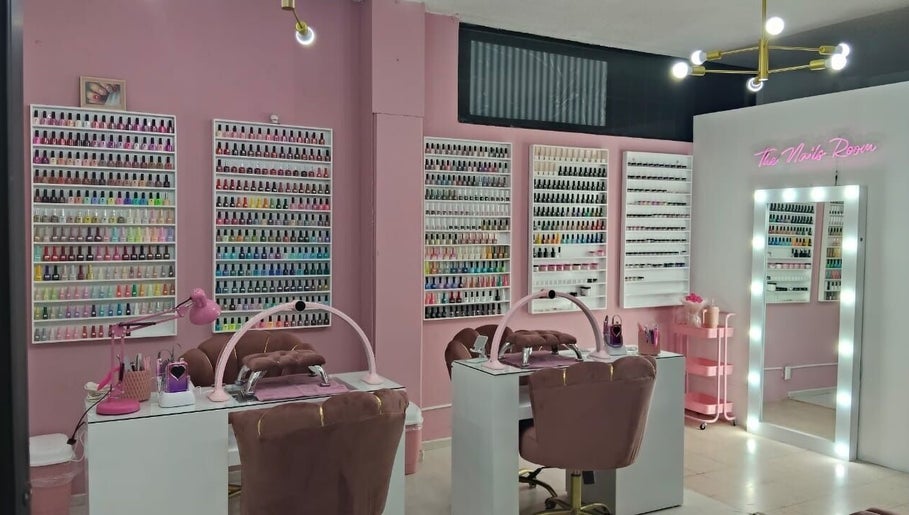 Elegante salón de uñas en The Nails Room, Ciudad Sahagun, MX, con estantes de esmaltes coloridos y espejos iluminados.