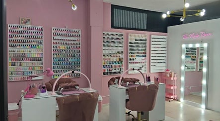 Elegante salón de uñas en The Nails Room, Ciudad Sahagun, MX, con estantes de esmaltes coloridos y espejos iluminados.