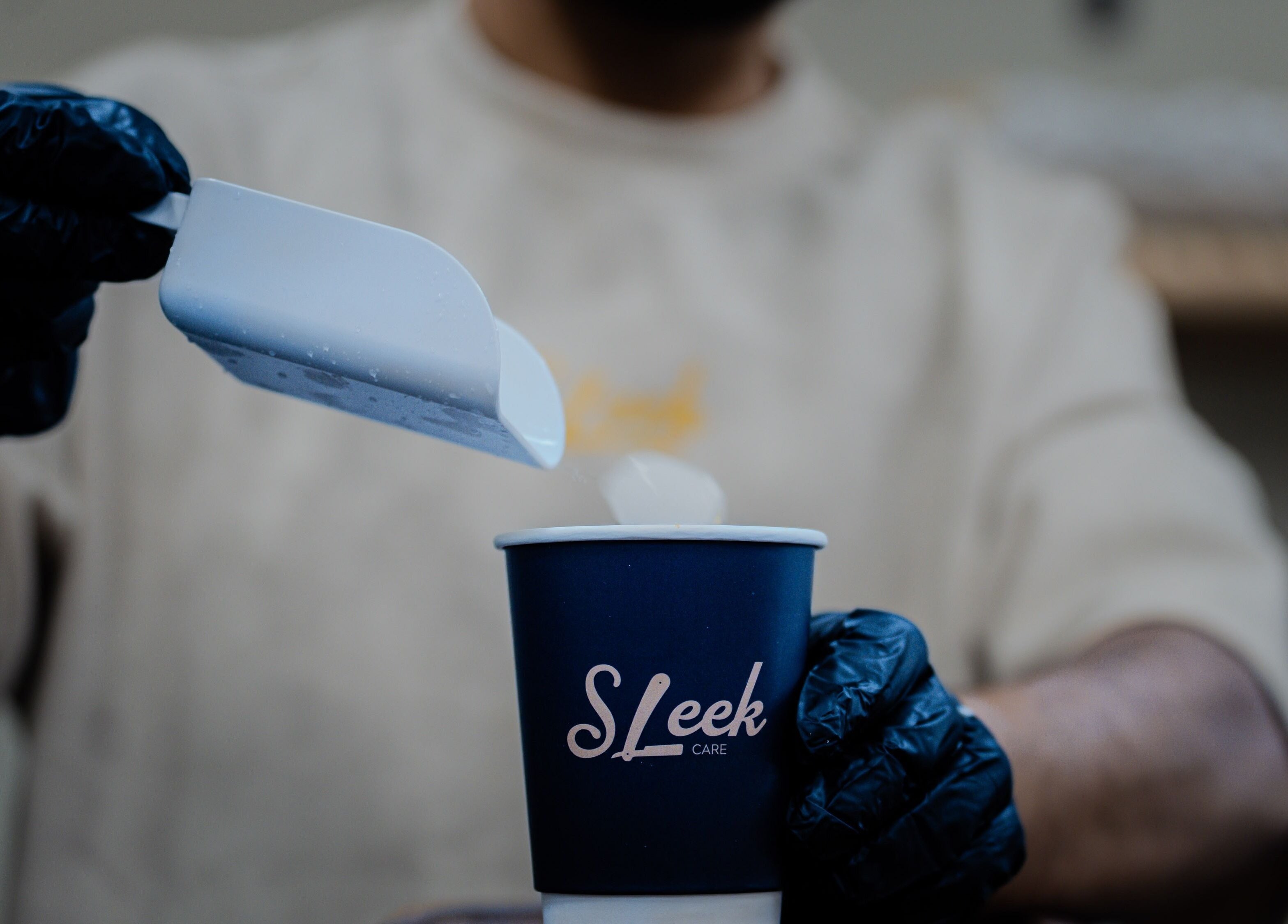 Gloved hand prepares ice drink at Sleek Care, Riyadh, Riyadh Province, SA, enhancing refreshment experience.
